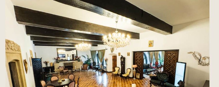 The villa's interwar salon, with exposed timber beams, two crystal chandeliers, a fireplace and period furniture